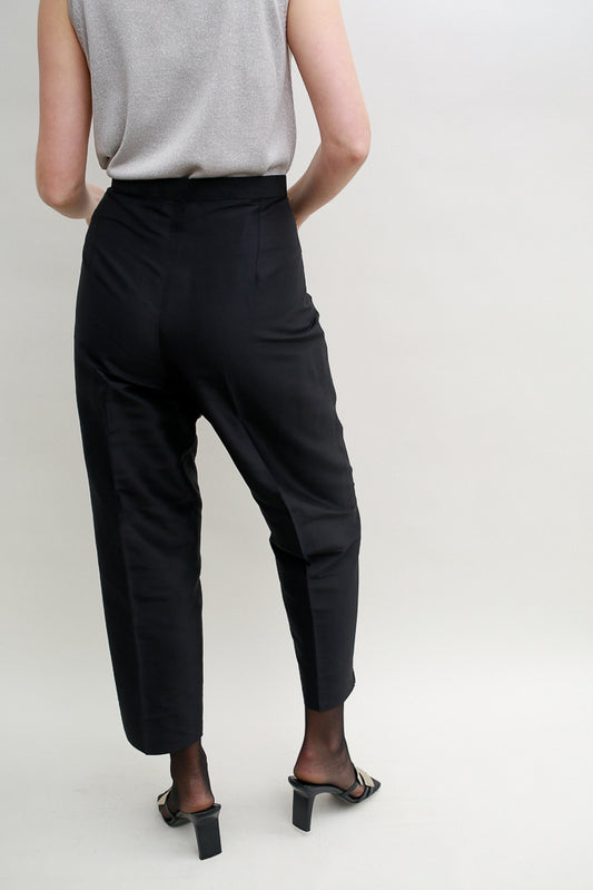 Silk carrot trousers in black with high waist on a model with silver top, shot from the back. Re-Nou